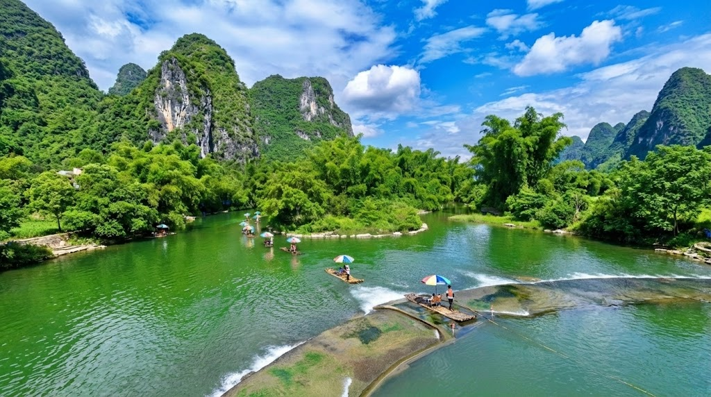 Tourists riding traditional bamboo rafts with colorful umbrellas on the emerald green Yulong River in Yangshuo, Guilin. The rafts are navigating a small weir amidst lush bamboo groves and karst mountains.